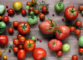 Red and green tomatoes on a wooden surface.
