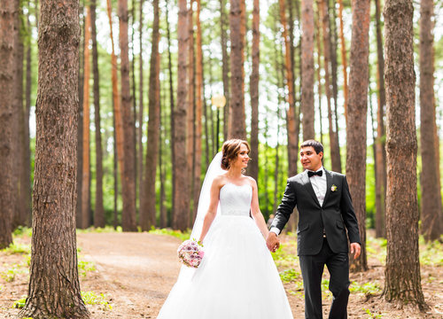 Groom and Bride in a park. Bridal wedding bouquet of flowers