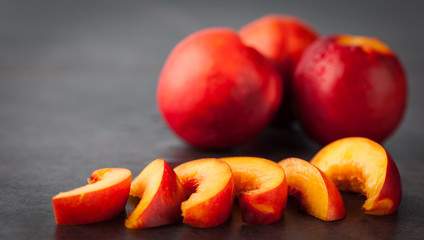 Yellow nectarine peach - whole fruit and slices on dark grungy  background. Shallow depth of field.
