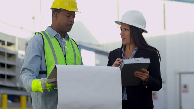Businesswoman and construction worker discuss project