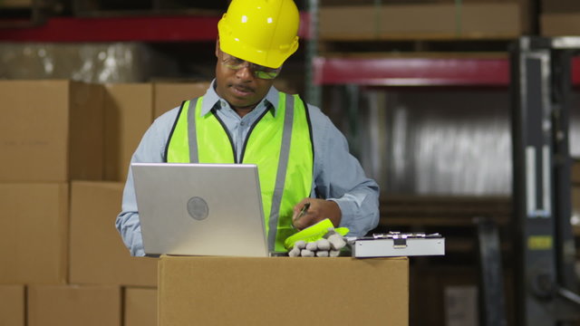 Man in warehouse working on laptop computer