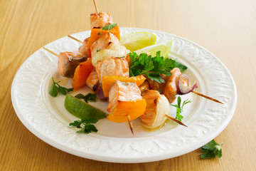 Shashlik of salmon with vegetables and white sauce.