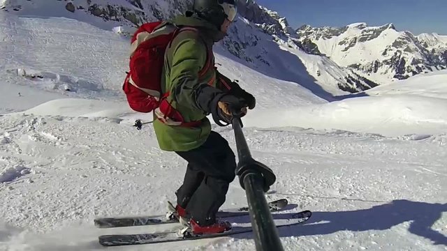 Skier on a piste of Engelberg in switzerland with downhill selfie, using an  action cam on the end of his pole.