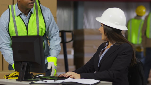 Man and woman work on computer in warehouse