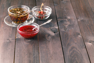cup of tea on wooden table over wooden background with raspberry