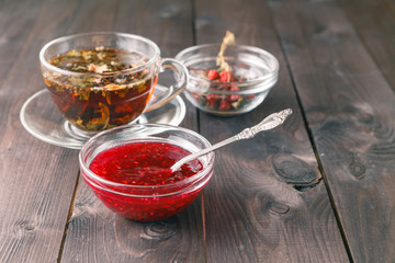 raspberry jam on table with cup of herbal tea