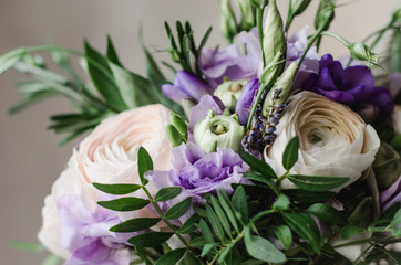 Beautiful rustic wedding bouquet of violet and white ranunculus lavender flowers with satin lilac tape on a white background
