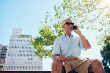 Mature man sitting outdoors talking on cell phone