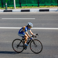 Fototapeta na wymiar Female cyclist rides a racing bike on road