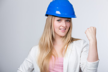Junge Ingenieurin mit Helm zeigt ihre Faust und ihre Kraft
