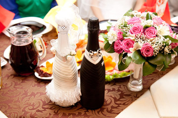 Two bottles of champagne in bride and groom clothes on restaurant table