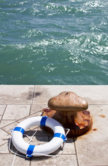 Rusty iron bollard and lifebuoy on a sea pier
