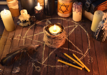 Black candle in the circle with pentagram and magic candles.