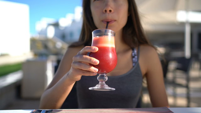 Healthy eating unrecognizable woman drinking vegetable smoothie juice. Young person at restaurant table sipping on cold pressed or blended fruits and red beets. Juicing detox cleanse diet trend.