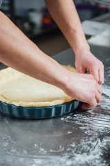 Male hands cooking pie in baking pan