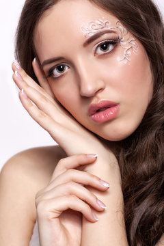 Close-up portrait of young woman with face art  make up and mani