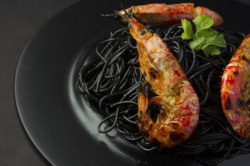 Black spaghetti (noodles) with shrimp over dark background