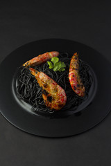 Black spaghetti (noodles) with shrimp over dark background