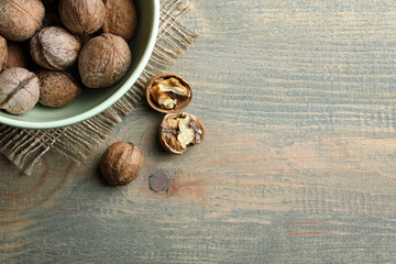a Cup full of nuts standing on the burlap around a few broken nuts on a wooden table