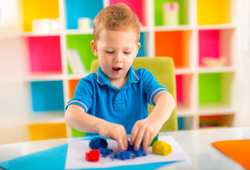 Cute little boy moulds from plasticine on table