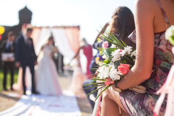 Wedding ceremony outdoors, focus on flowers bouquet
