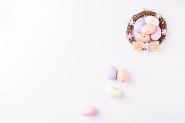 Easter eggs painted in pastel colors in the nest on white