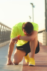 Tired urban jogger making a pause after forcing his body on a big bridge.