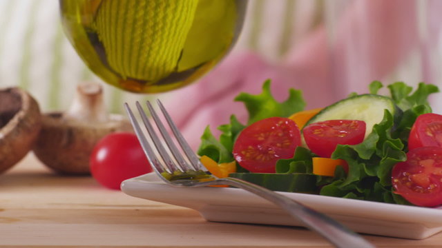 Pouring olive oil onto fresh salad