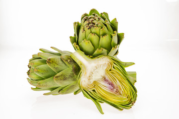 Obraz premium Fresh artichokes, one cut in half, isolated on white background.