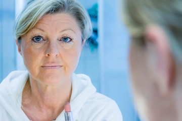 Fototapeta premium gepflegte dame mit lippenstift vor dem spiegel