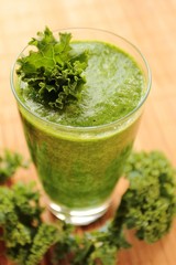 Clouseup view on a glass with green smoothie with fresh kale leafs