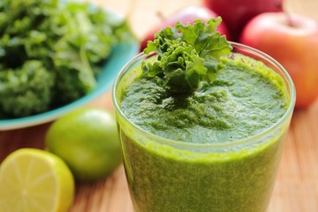 Glass with smoothie with green kale leafs, apple and lime