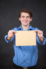 Businessman holding empty paper sheet front of head on blackboar