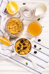 Breakfast concept with corn flakes, milk, dry cranberry and orange juice