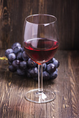 Glass of red wine and grapes. Toned vintage image. Selective focus