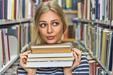 Young college woman in library holding books.