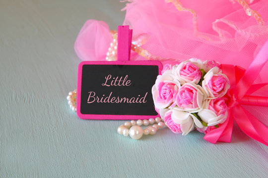 Small girls party outfit: crown and wand flowers next to small chalkboard with phrase LITTLE BRIDESMADE: on wooden table. bridesmaid or fairy costume. selective focus