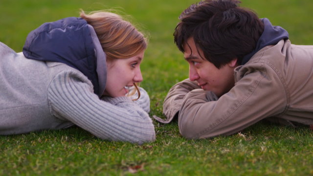 Young couple laying in grass talking