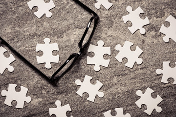 Glasses and blank puzzel pieces. Concept of business challenge, teamwork and solution. - 105340055
