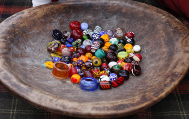 different colorful glass beads on vintage wooden plate