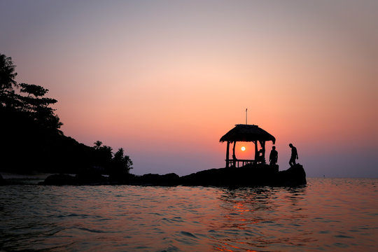 Silhouette of three people on beach at sunset