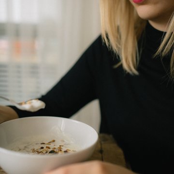 Young Woman Eating Yogurt And Granola Breakfast