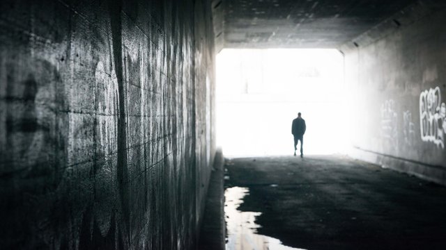 Silhouette of a man walking through tunnel