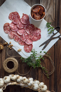 Overhead view of salami slices with garlic on wooden table 