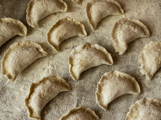 Homemade dumplings, uncooked, only molded on a linen tablecloth.