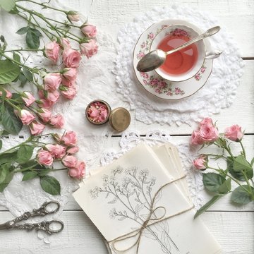 Overhead view of pink roses and cup of tea on table