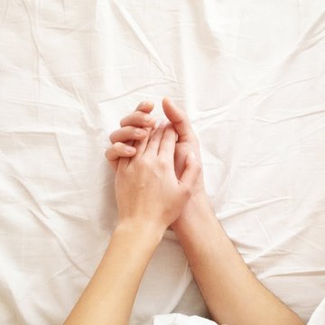Close-up of a Couple lying in bed holding hands
