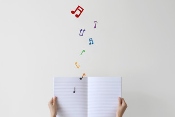 Woman holding notebook with musical notes flying off page 