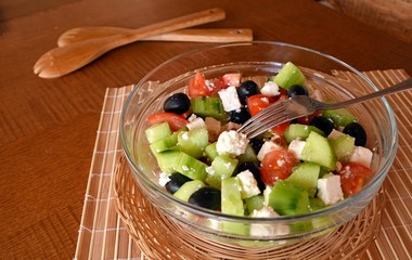 Fresh mixed vegetable salad with pieces of cheese on a glass bowl