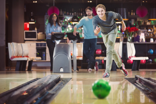 Smiling happy man is throwing the bowlingball